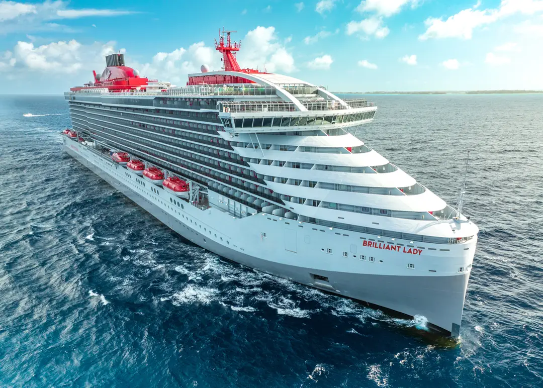 Virgin Voyages' Brilliant Lady underway at sea, photographed from the bow in bright daylight